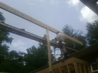 Carpenter setting a ridge beam over a new addition frame — Ice Dam Removal by Roofing Brothers in Hye