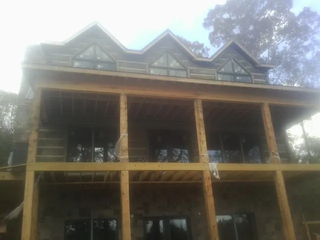 Dormers and porch framing on a large log home under construction — Roof Coating work by our crew in Hye