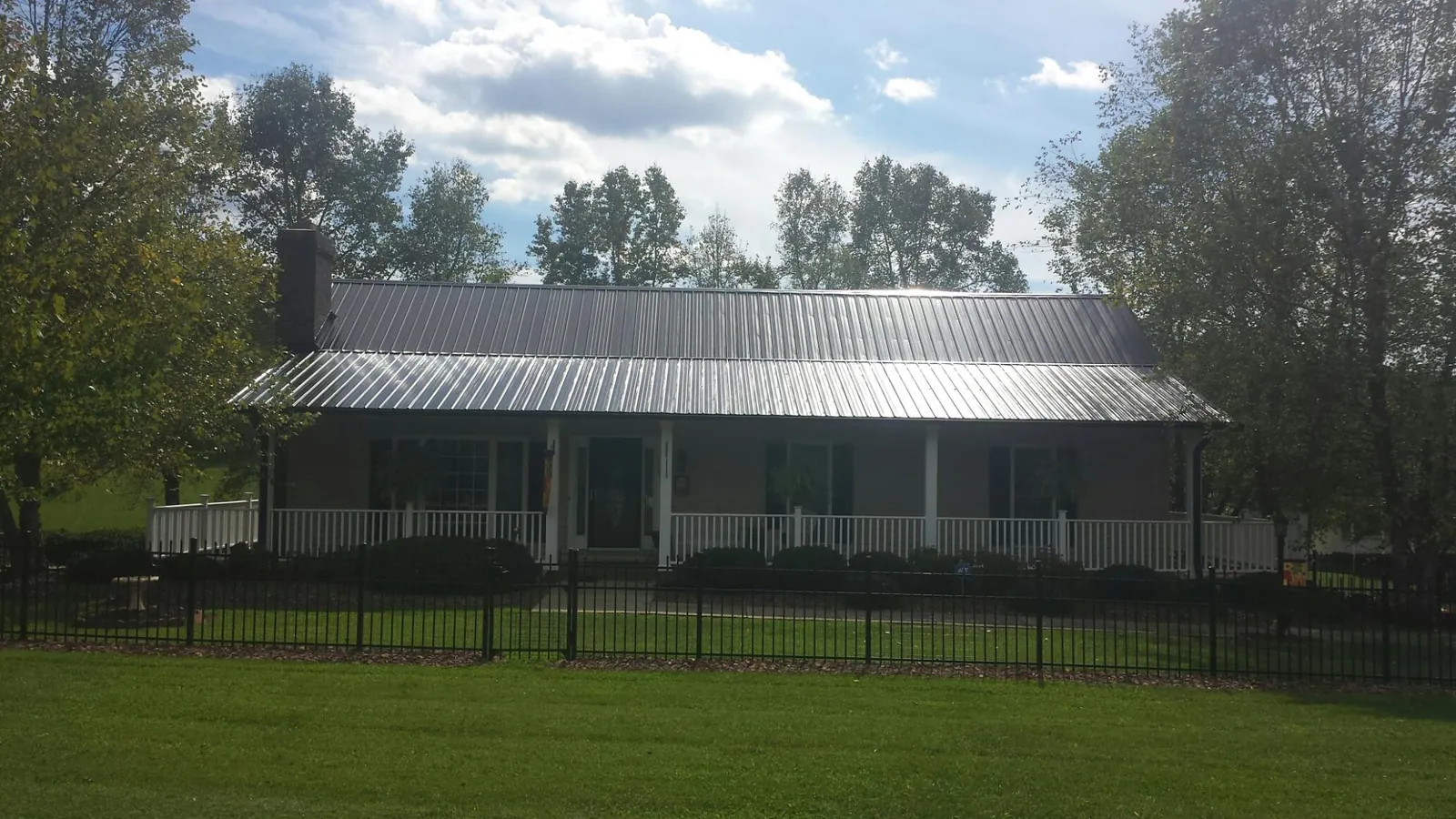 Gray metal roof on a brick ranch with a full width front porch — Gutter Guard Installation work by our crew in Hye