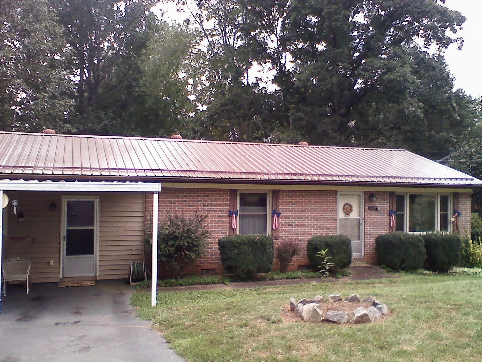 Bronze metal roof and carport on a brick ranch home — Roof Repair work by our crew in Hye