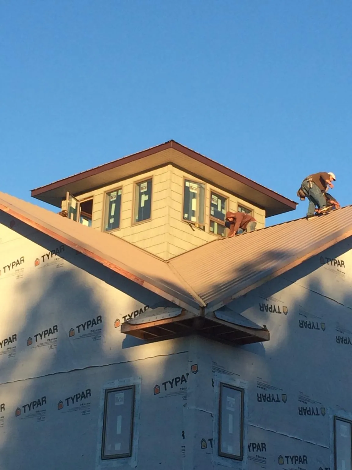 Roofers working around a rooftop cupola on a new metal roof at sunset — Roof Waterproofing in Hye by Roofing Brothers